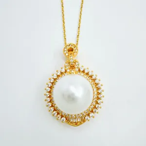 Gold pearl pendant necklace detail featuring a large central pearl with crystal rhinestone halo.