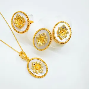 Primo piano di gioielli floreali vintage placcati in oro con madreperla e cristalli.