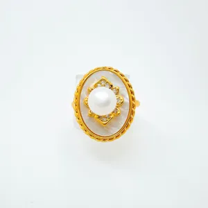 Dettaglio anello perla ovale vintage, cornice dorata con strass lucidi e raffinati.
