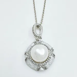 Detailed shot of exquisite silver pearl pendant necklace with sparkling cubic zirconia halo.