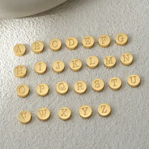 Vue rapprochée détaillée de perles breloques pendentifs de lettres en acier doré.