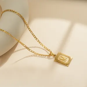 Primer plano del collar de acero inoxidable dorado para hombre con colgante cuadrado letra M.