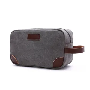 Classic grey canvas toiletry bag with brown leather handle and accents, ideal for travel.