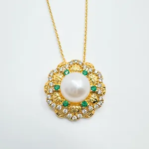 Squisita collana con ciondolo in perla dorata con pietre verdi e diamanti scintillanti.