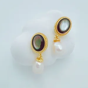 Vue détaillée de magnifiques boucles d'oreilles pendantes en nacre et perle dorée.