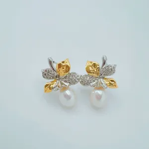Exquisites Perlenohrring-Detail mit Blättern, elegantes Gold- und Silberton-Schmuckstück.