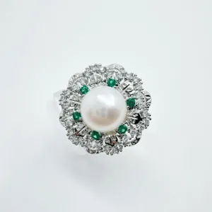 Primo piano dettagliato dell'anello di perle vintage con pietre verdi e zirconi splendenti.