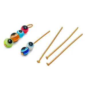 Close-up view of colorful glass evil eye beads and golden metal jewelry making pins details.