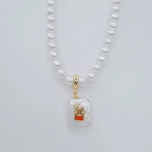 Elegant freshwater pearl necklace detail featuring a unique artistic pendant and gold clasp.