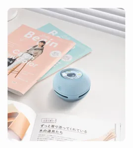 Detailed view of the portable mini desktop vacuum cleaner in a clean study setup with books.