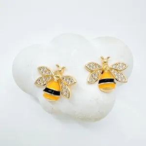Close-up of elegant gold plated crystal bee stud earrings with cute enamel striped body details.