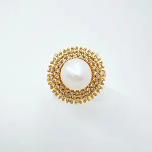 Close-up detail of luxury gold-plated pearl and cubic zirconia sunburst pendant accessory.