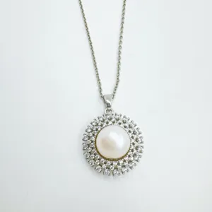 Close-up detail of the elegant pearl pendant with sparkling rhinestone halo on a fine chain.