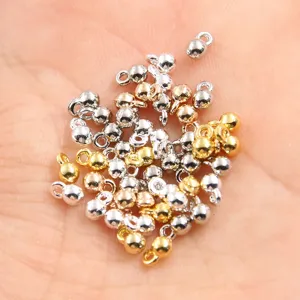 Nahaufnahme von kleinen Metallkugel-Anhängern mit Öse, DIY Schmuckperlen in Gold und Silber.