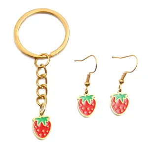 Detailed shot of a cute strawberry charm jewelry set including a keychain and earrings.