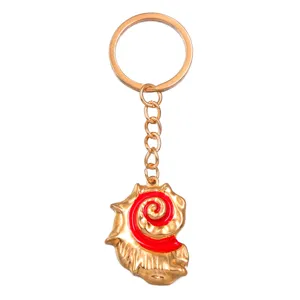 Gedetailleerd aanzicht van de gouden legering sleutelhanger met rode schelp hanger.