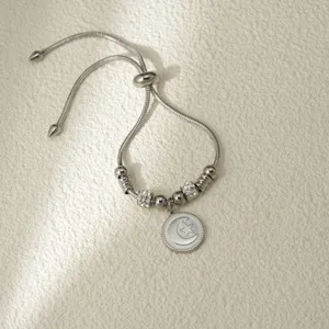 Vista detallada de la pulsera ajustable de acero inoxidable plateado con colgante de luna y estrella.