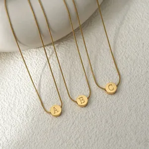 Gros plan de colliers ras de cou minimalistes en acier inoxydable doré avec pendentifs lettres A, B, C.