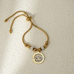 Pulsera ajustable de acero inoxidable con mal de ojo dorado, detalles elegantes.