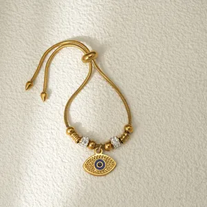 Primer plano de pulsera ajustable de mal de ojo dorada con cuentas de pedrería de acero inox.