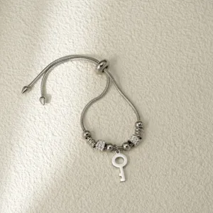 Vista detallada de una pulsera de cadena de serpiente plateada con colgante de llave.