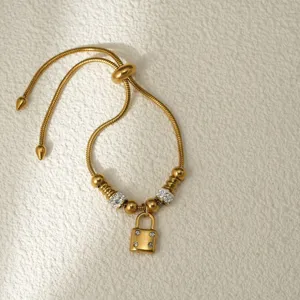 Pulsera ajustable de acero inoxidable dorado con colgante de candado en detalle elegante.