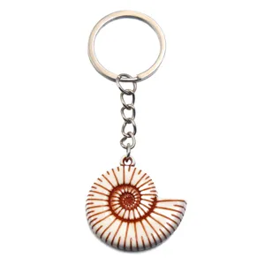 Close-up detail of acrylic ammonite shell keychain pendant with metal ring and chain hardware.