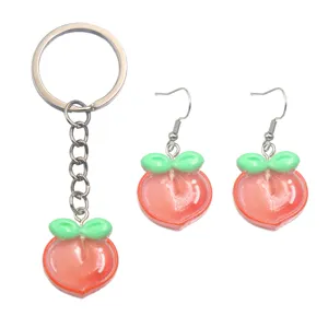 Peach resin keychain and earrings set detail view, cute fruit charm accessory close up.
