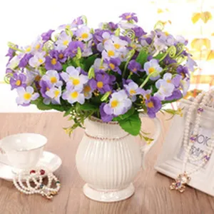 Bouquet di fiori artificiali con piccoli fiori viola in un vaso di ceramica bianca per la casa.