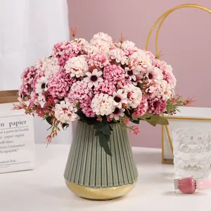 Dettaglio di un bouquet di fiori artificiali rosa e bianchi in un vaso di ceramica scanalato.