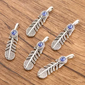 Close-up detail of silver feather pendants with blue evil eye charms, zinc alloy DIY jewelry.