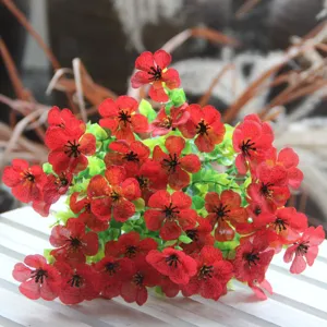 Detailed close-up of artificial flower bouquet with red petals and green leaves for decor.