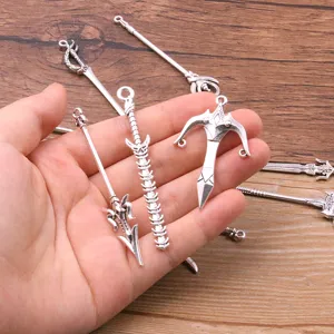 Close-up of silver alloy weapon charms, miniature swords and bows for DIY jewelry craft.