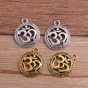 Close up of vintage alloy Om symbol charms, hollow round 3D pendants in gold and silver colors.