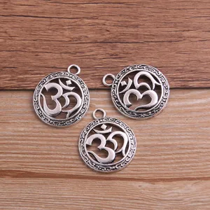 Close-up detail of vintage silver OM symbol hollow metal charms for DIY jewelry making and pendants.