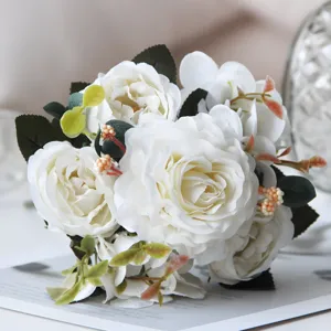 Primo piano dettagliato di bouquet di fiori di peonia rosa artificiale bianca con foglie verdi.