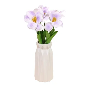 Künstlicher lilafarbener Tulpenblumenstrauß in einer weißen geometrischen Vase für Zuhause.