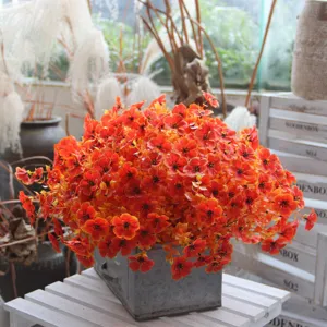 Artificial orange flower potted plant home decoration floral arrangement detail view.