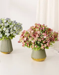 Primer plano detallado de hermosos ramos de flores artificiales en elegantes floreros verdes.