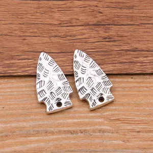 Closeup of silver alloy hammered arrow pendant charms for DIY jewelry making and phone accessories.