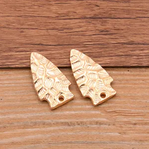 Detailed close-up view of golden arrow shape alloy DIY pendant charms with hammered texture.