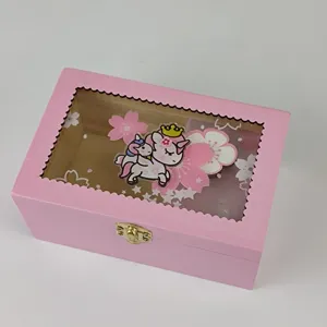 Pink wooden jewelry box detail with transparent window, unicorn pattern and golden clasp lock.