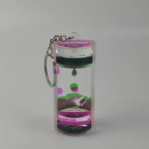 Close-up detail of dual-color liquid motion oil drop keychain with floating pink and green droplets.