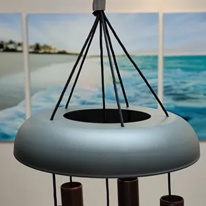 Close-up detail of the modern metal wind chime with grey top cap and hanging strings.