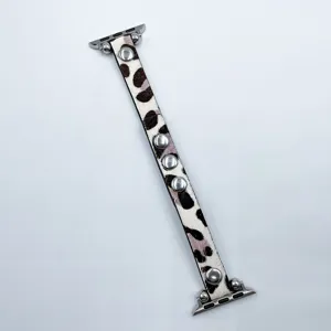 Gros plan sur le bracelet de montre en cuir léopard avec des rivets métalliques et attaches.