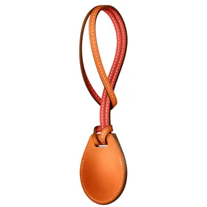 Detailed view of leather airtag case keychain strap, premium orange finish with white stitching.