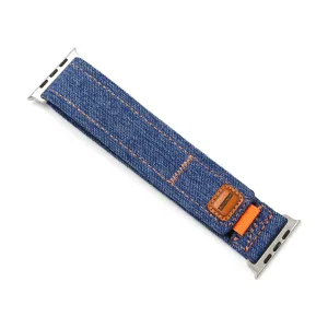 Gros plan sur les détails du bracelet de montre en denim bleu avec des coutures orange et métal.