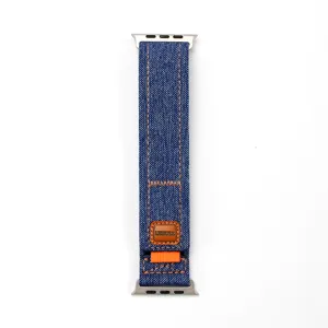 Gros plan détaillé du bracelet de montre en jean bleu avec coutures orange et étiquette.
