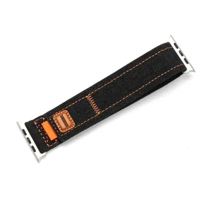 Gros plan sur le bracelet de montre en denim noir avec coutures orange contrastées et connecteur.