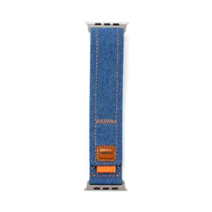 Détail de bracelet de montre en denim bleu avec coutures orange et connecteurs métalliques.
